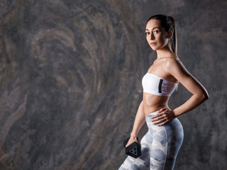 Sporty beautiful woman with dumbbells makes fitness exercising at black background to stay fit.