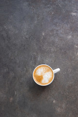 Cappuccino cup with milk foam on brown concrete background with copy space. Coffee time concept.