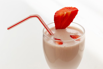 Strawberry smoothie in a glass with a straw and fresh strawberry