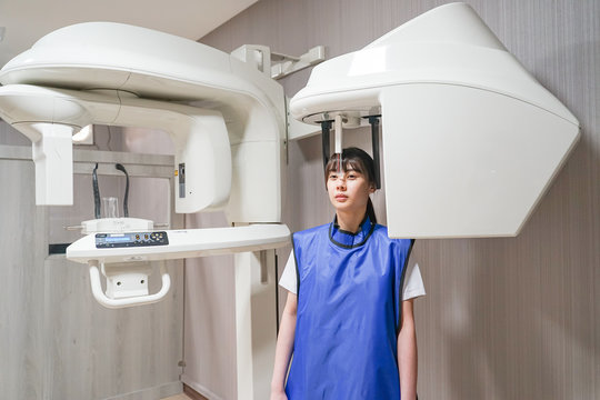Young asian patient woman standing in dental x-ray machine for dental radiography.