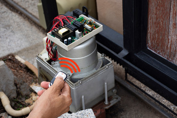 Technician man hand using remote control, testing and checking the functional of auto door....