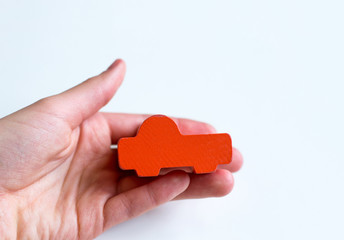 photo hand holds orange toy wooden car white background
