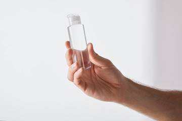 cropped view of man holding hand sanitizer on grey background