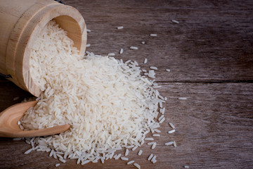 White rice in wooden bucket isolated on wood table background. 