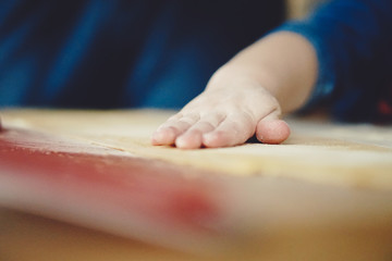 Obraz na płótnie Canvas childs hands kneading dough on table