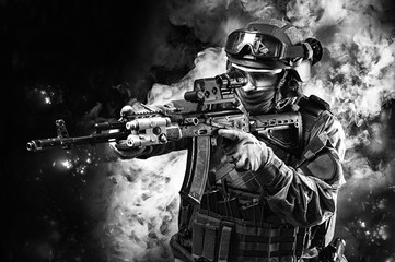 Portrait of a special forces soldier who is aiming at a collimator sight of a machine gun. The...