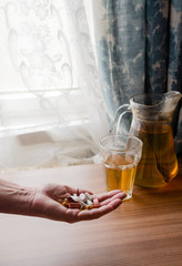 Woman holds pills in her hand - in the background herbal tee - vitamins -  dietary supplements - immune system boost