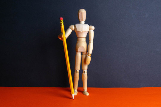 The figure of a wooden man holds pencil. Front views - Powered by Adobe