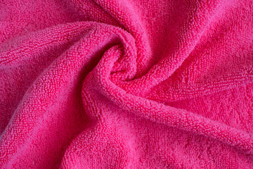 Fototapeta na wymiar Wrinkled bright pink microfiber cloth texture of microfiber towel closeup. Pink microfiber cloth for cleaning objects and surfaces. Hygienic cleaning towel. fabric background.
