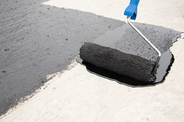 Worker applies bitumen mastic on the foundation