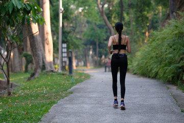 young woman doing exercise in the park and listening music