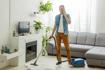 Coronavirus pandemic. A man with a vacuum cleaner in his apartment. Home Office. Quarantine. Remote work. A man in a business shirt and underpants holds.