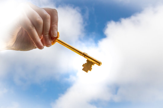 A Hand Holding a Golden Key in the Clouds