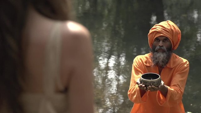 The old monk passes the holy grail, the monk gives the girl a cup of sacred fire. A girl walks through the deserted places of India, walks through the jungle, carries sacred fire. 