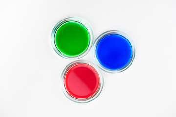 three cups of petri dishes with colored liquid
