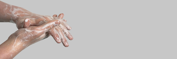 Fototapeta premium Hands of a young guy in soapy foam on a gray background. Hand washing. Minimal hygiene, virus protection concept.
