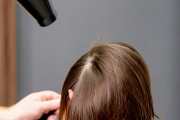 Fototapeta premium Hairstylist dries hair of woman.