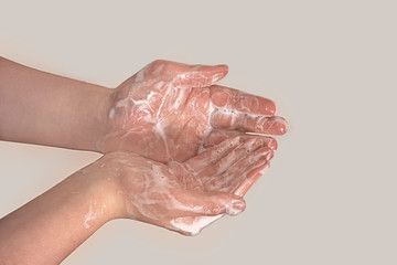 Fototapeta premium Hands of a young guy in soap foam on a gray background. Hand washing. Minimal hygiene, virus protection concept.