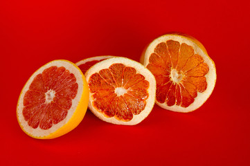 Chips of dried grapefruit sliced in thin circles, shot on a red background. Background for vegetarianism, healthy and wholesome food.