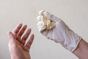 Women's hands with latex gloves, removing gloves safely and effectively to avoid contagion.