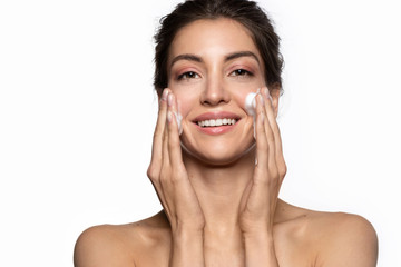 Beautiful woman washing with foam cleansing face gel or soap look at camera.