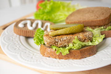 Veggie bean burger sandwiches with mayo, lettuce, tomatoes and pickled cucumber