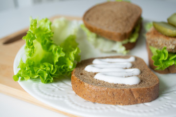 Veggie bean burger sandwiches with mayo, lettuce, tomatoes and pickled cucumber