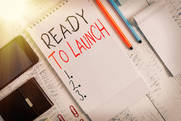 Handwriting text Ready To Launch. Conceptual photo an event to celebrate or introduce something new to market Smartphone man wallet clips notebook pens ballpoints note pad wooden table