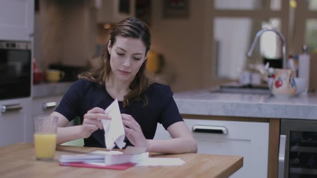 Young adult woman opening bills at home