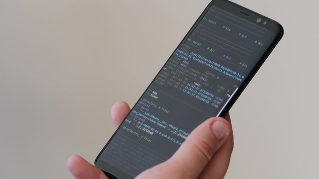 A close up on a hand holding a mobile phone devise that is getting hacked and seeing a security breach on the smartphone's screen.
