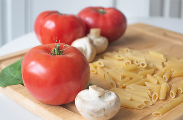 Ingredients for tradional italian pasta dish: dry penne, tomatoes, basil, mushrooms and garlic