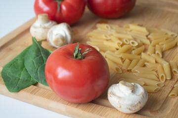 Ingredients for tradional italian pasta dish: dry penne, tomatoes, basil, mushrooms and garlic