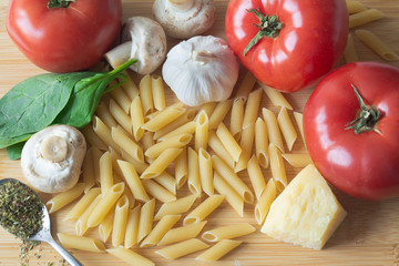 Ingredients for tradional italian pasta dish: dry penne, tomatoes, basil, mushrooms and garlic
