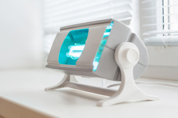 A working ultraviolet lamp on a white background. The concept of protecting and cleaning rooms and objects from bacteria and viruses. Medicine and healthcare.