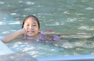 Fototapeta na wymiar Smiling cute little girl in swimming pool