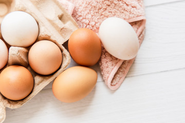 Brown and white organic chicken eggs in a brown paper box placed on a white wooden table. Eggs provide protein, suitable for health lovers.