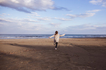 Little fashionable girl runs near the sea