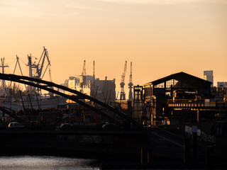 Hamburg, Germany: October 31, 2019: A beautiful sunset on the Elbe river in Hamburg with a Baumwall subway station and port crates in background.