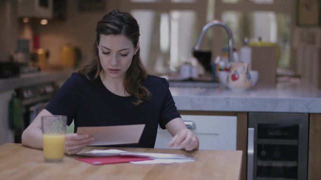 Young adult woman opening bills at home