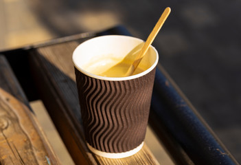 Morning coffee. A brown paper cup with a hot drink on a bench on the street.