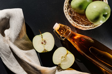 still life with apples and a bottle of apple cider or juice, or vinegar on a dark background. The...
