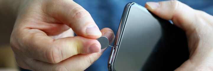 Male hands getting sim card slot of his smartphone out