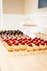 Leckere cup cakes mit Frischkäsecreme und verschiedenen Obst topings