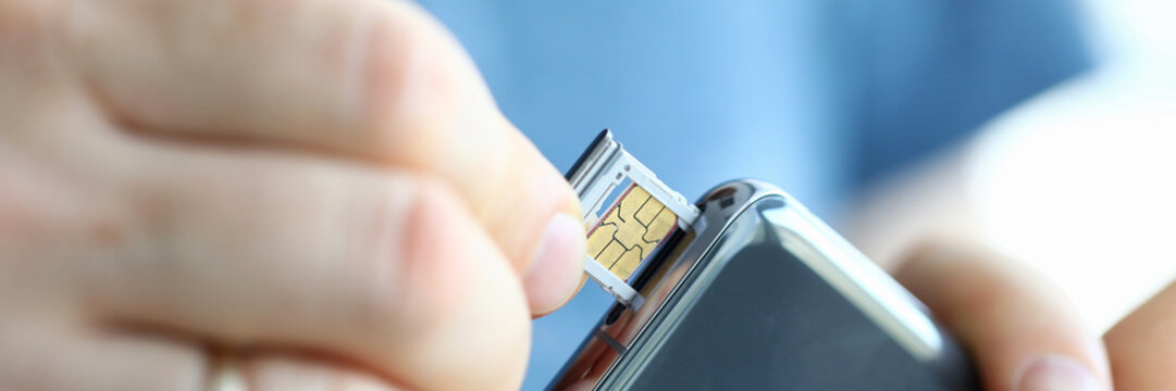 Male hands getting sim card slot of his smartphone out