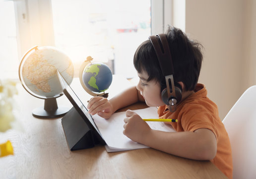 Portrait of preschool kid using tablet for his homework,Soft focus of Child doing homework by using digital tablet searching information on internet, Home schooling education concept