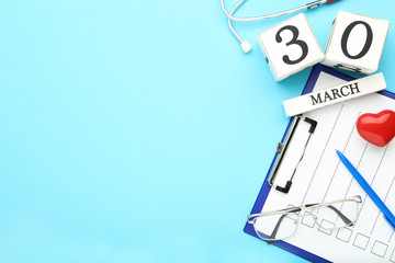 Clipboard with eyeglasses, red heart, cube calendar and stethoscope on blue background