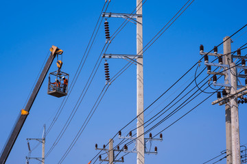 Low angle view and selective focus at  crane truck lifting 2 electricians in metal man basket to...