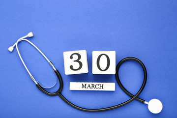 Stethoscope with white cube calendar on blue background
