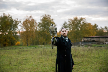 The concept of falconry. A man of European appearance with beard, with a leather glove and a...