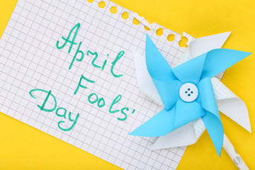 Text April Fool's Day with paper windmill on yellow background